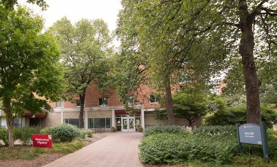 The front door of Sorin Hall at Hamline University, with a sign that says "Welcome Pipers!"