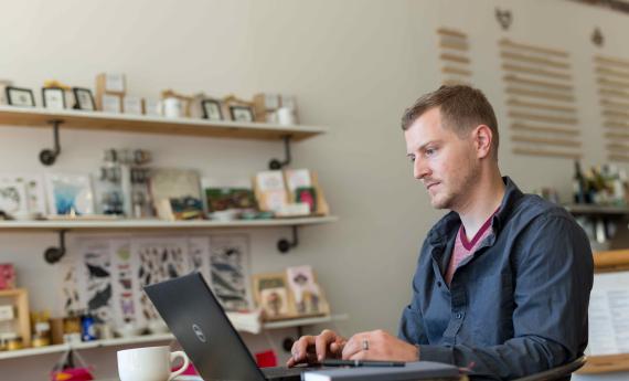 Hamline Student looking to a laptop in a coffee shop