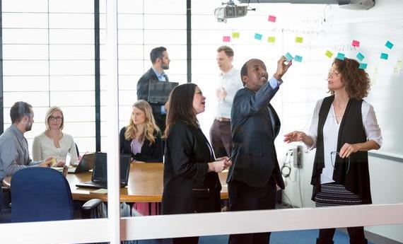 Hamline students and professor talking in front of a board 