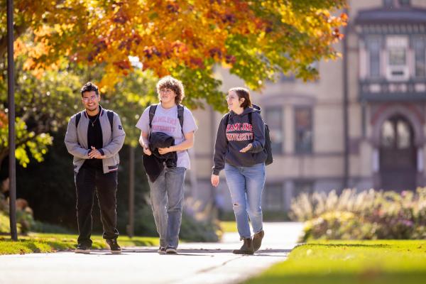 three students walking in front of old main