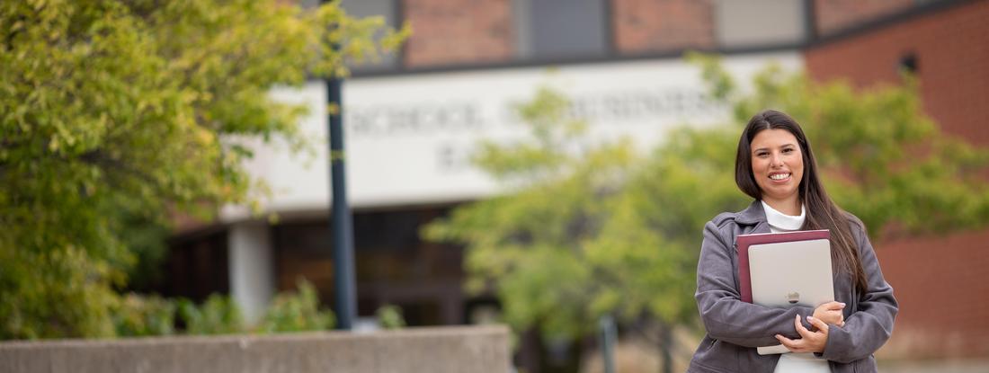 International Graduate Student holding a book in front of Hamline School of Business