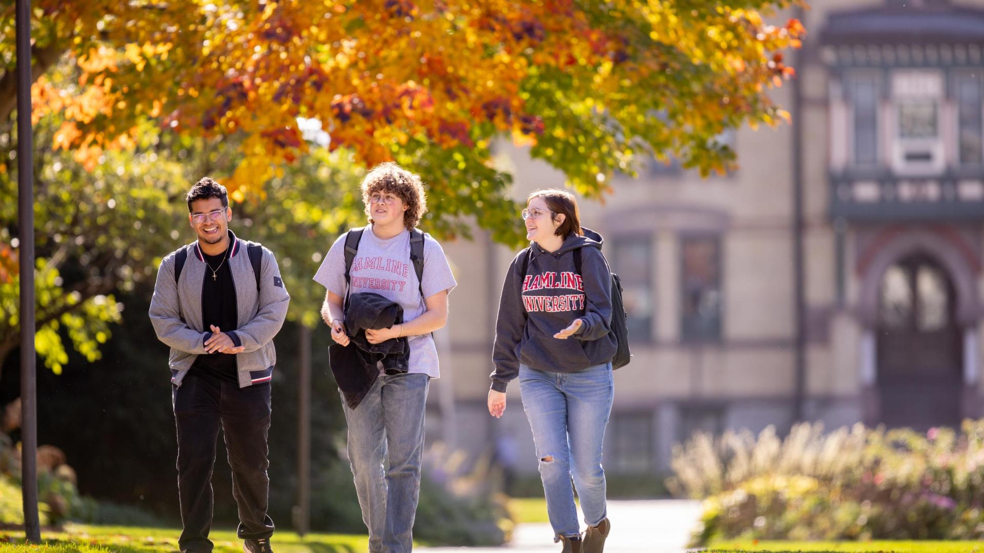 three students walking in front of old main