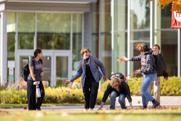 Students throwing leaves in front of Anderson